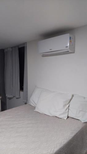 um quarto com uma cama branca e uma luz por cima. em Apart-hotel St° Antônio de Pádua em Santo Antônio de Pádua