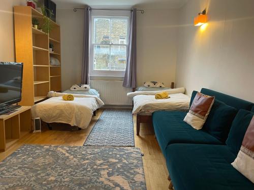 a living room with two beds and a couch at 10 min to The Heart of London - Zone 2 - Charming 2 bed Apartment in London