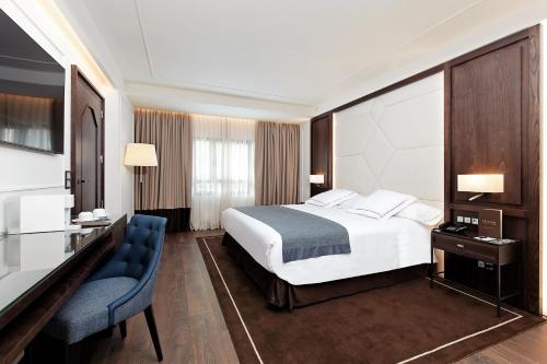 馬德里的住宿－馬德里克拉里奇酒店，配有一张床和一张书桌的酒店客房