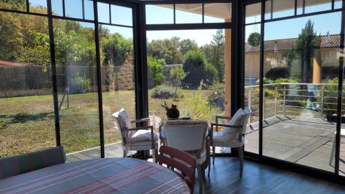 ein Raum mit Tisch und Stühlen und einem großen Fenster in der Unterkunft Alix au pays des Pierres Dorées in Alix