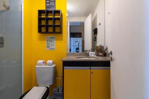 a yellow bathroom with a toilet and a sink at 360 Suítes Sé in Sao Paulo