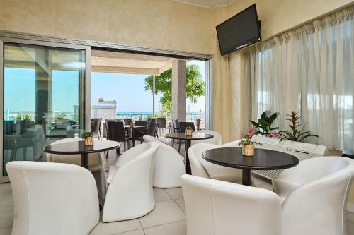 un restaurante con sillas y mesas blancas y TV en Hotel Piccadilly, en Bellaria-Igea Marina