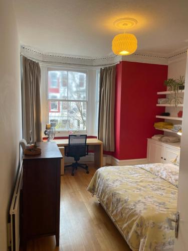 1 dormitorio con cama, escritorio y ventana en 15 min to The Heart of London - Charming 2 bed Apartment, en Londres