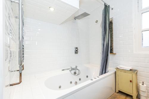 biała łazienka z wanną i prysznicem w obiekcie Unique Detached House wPrivate Courtyard, London w Londynie