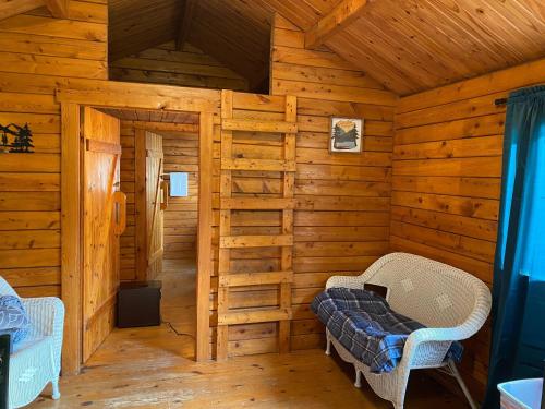 une cabane en rondins avec un lit et deux chaises dans l'établissement Homely Poolside Cabin, à Salisbury