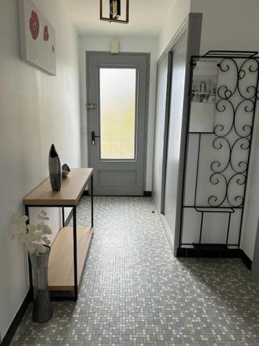 un couloir avec une porte et une table avec un vase dans l'établissement Le gîte de Marie, à LʼIsle-Jourdain