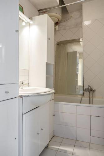 une salle de bain blanche avec un lavabo et un miroir dans l'établissement Sous le ciel de Paris, petite suite, à Paris