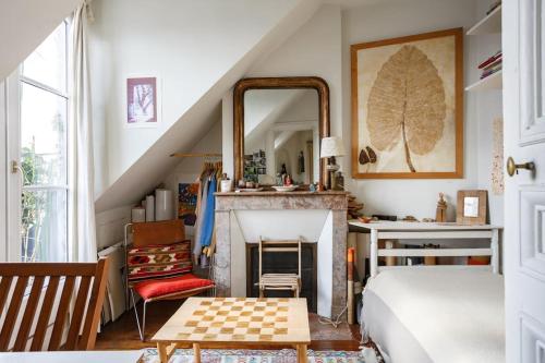 - une chambre avec un lit, un miroir et une cheminée dans l'établissement Sous le ciel de Paris, petite suite, à Paris