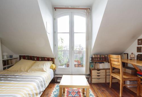 une chambre avec un lit, un bureau et une fenêtre dans l'établissement Sous le ciel de Paris, petite suite, à Paris