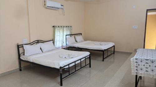 Cette chambre comprend 2 lits et une table. dans l'établissement HOTEL VITU SIA CALANGUTE BEACH, à Calangute