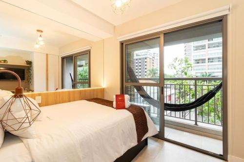 um quarto com uma cama e uma varanda em Zainalofts7 Moema - 1km Ibira e 200m metrô 213 ID em São Paulo