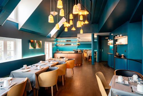 un restaurant avec des murs bleus, des tables et des chaises dans l'établissement Hôtel de la Cité, à Saint-Malo