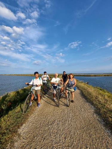 a group of people riding bikes on a path by the water at Comacchio Experience - Ospitalità Diffusa in Lido di Pomposa