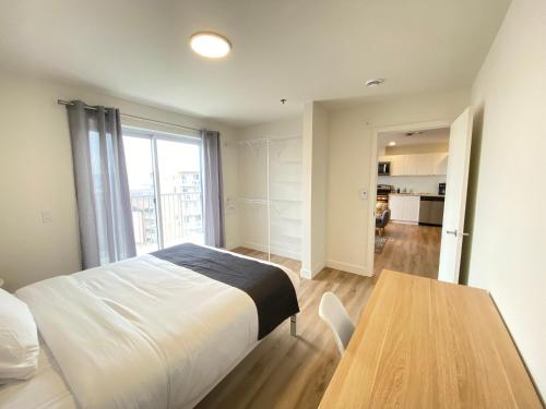a bedroom with a bed and a wooden table at APPART-HOTEL L'UNI in Quebec City