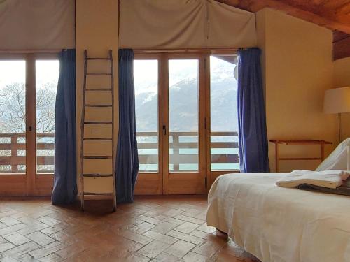 a bedroom with a bed with a ladder and windows at Villa Rustica in Sorico