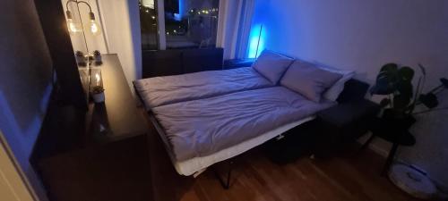 een klein bed in een kamer met een blauw licht bij Relax in a cozy studio overlooking downtown in Tromsø