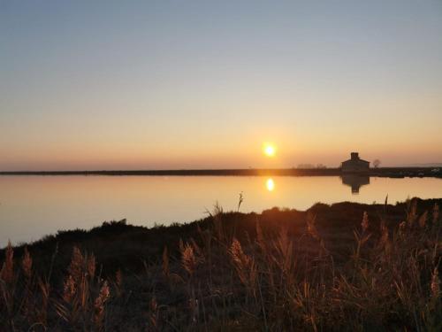 a sunset over a body of water with a lighthouse at Comacchio Experience - Ospitalità Diffusa in Lido di Pomposa