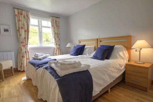 a bedroom with a large bed with blue pillows at No1 The Links Apartment, Brora in Brora