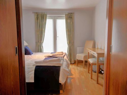 a bedroom with a bed and a desk and a window at No1 The Links Apartment, Brora in Brora