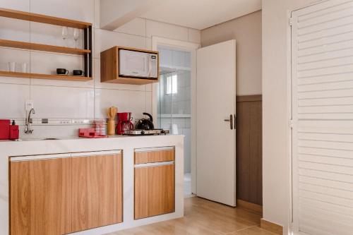eine Küche mit einer Spüle und einer Mikrowelle in der Unterkunft Studio novo em Santa Mônica ASK001 in Florianópolis