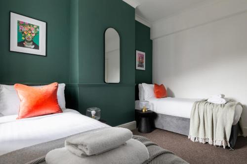2 camas en una habitación con paredes verdes en Perry Place - Forest Hill- 3 bed house en Londres