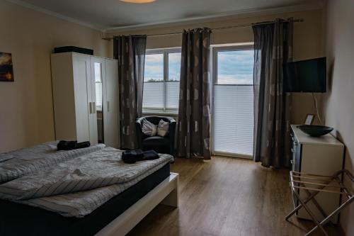 a bedroom with a bed and a chair and windows at Haus Strandglück - Urlaub mit Blick auf den Dümmer See in Lembruch