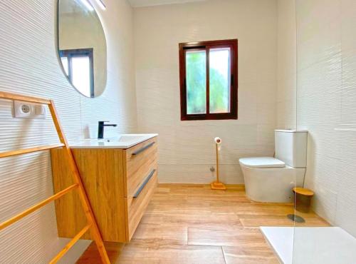 een badkamer met een wastafel, een toilet en een spiegel bij Casa Fatima in El Palmar
