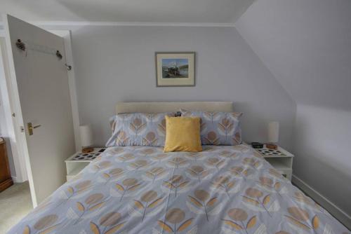 Dormitorio con cama con almohada amarilla en Crossing Cottage, Brora en Brora