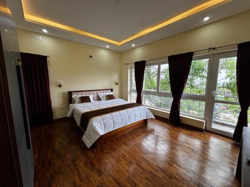 een grote slaapkamer met een bed en grote ramen bij Sanjay Home Stay in Kodaikānāl