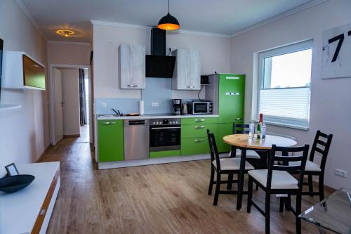 a kitchen with green cabinets and a table and chairs at Haus Strandglück - Urlaub mit Blick auf den Dümmer See in Lembruch