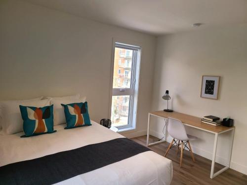 a bedroom with a bed and a desk and a window at APPART-HOTEL L'UNI in Quebec City
