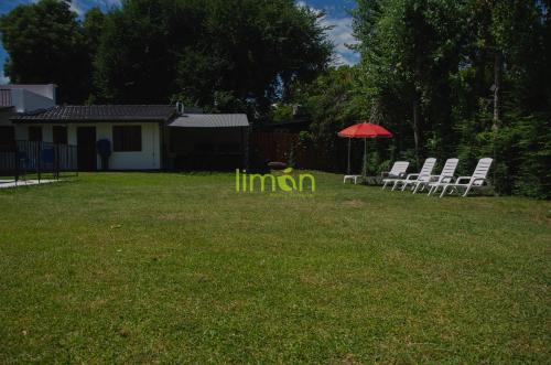 a group of lawn chairs and an umbrella in a yard at Casa Amplia 5 personas con Jardin y Parrilla in Tigre