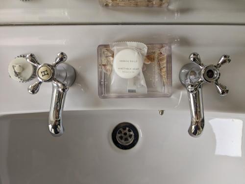 a bathroom sink with two faucets and a soap container at Mocha Newcastle in Galway