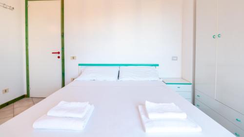 - une chambre avec un lit blanc et 2 serviettes dans l'établissement Martini Green House, à Torre Grande