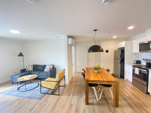a kitchen and living room with a table and a blue couch at APPART-HOTEL L'UNI in Quebec City