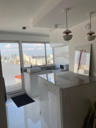 a kitchen with white cabinets and a view of the city at 14eme et dernier étage - 3 pieces "Arty" de 65 m2 avec vue panoramique ! in Créteil