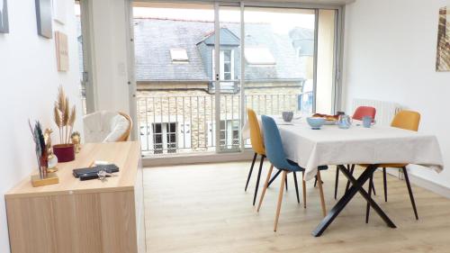 une table et des chaises dans une pièce avec une grande fenêtre dans l'établissement Ti An Alré, appartement 4 p en centre ville, à Auray