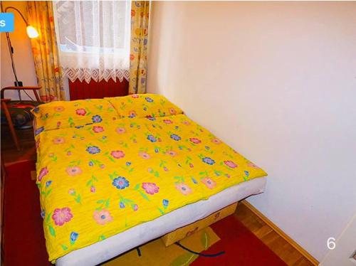 ein Schlafzimmer mit einem gelben Bett mit Blumen darauf in der Unterkunft Ardent Apartman in Siófok