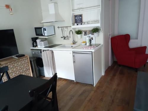 une petite cuisine avec un évier et un fauteuil rouge dans l'établissement Ancien Atelier Parisien Grand 2 pièces, à Paris