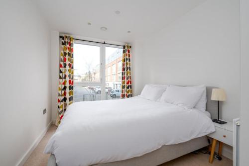 um quarto branco com uma cama grande e uma janela em GuestReady - Modern lodge with garden em Londres