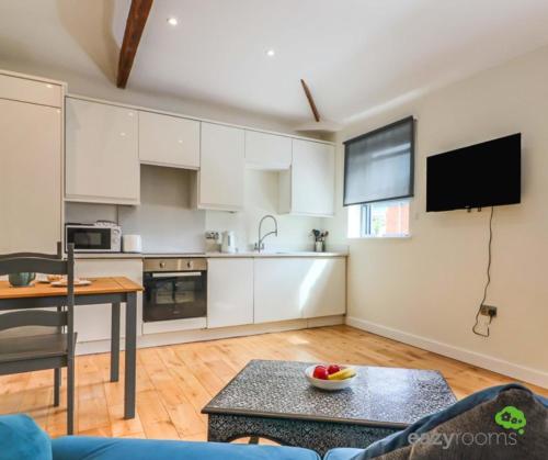 a kitchen with white cabinets and a table in a room at Cambridge Mews in Cleethorpes
