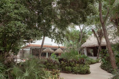 a resort with a pathway leading to a building with trees at Prana Boutique Hotel Tulum in Tulum
