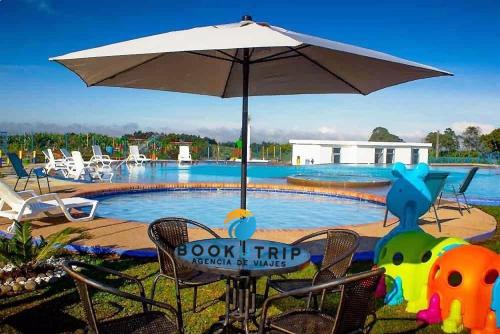 a swimming pool with an umbrella and chairs and an inflatable at APARTAHOTELES BOOKUTRIP 2km PARQUE DEL CAFÉ in Montenegro