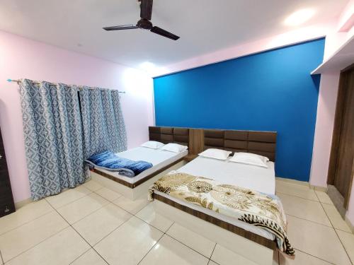 2 Betten in einem Zimmer mit blauer Wand in der Unterkunft Shridham Homestay in Ujjain
