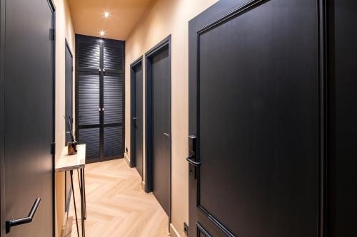 a hallway with black doors and a wooden floor at Breda City Apartments in Breda