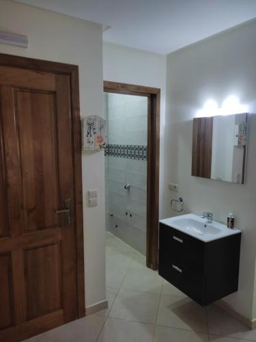 baño con lavabo, espejo y puerta en Appartement 3, en Agadir