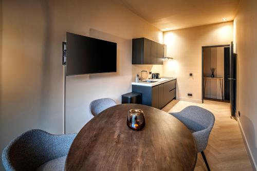 Habitación con mesa de madera, sillas y cocina. en Breda City Apartments, en Breda