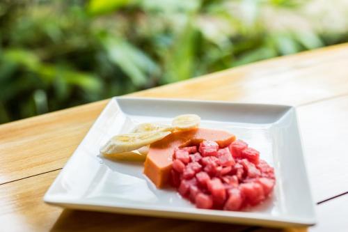 a white plate with fruit on a wooden table at Drake Bay Getaway Resort by Sandglass in Drake