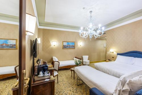 a hotel room with two beds and a chandelier at Hotel Colombina in Venice