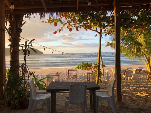 een tafel en stoelen op een strand met uitzicht op de oceaan bij Bucana Beach Camp in El Nido